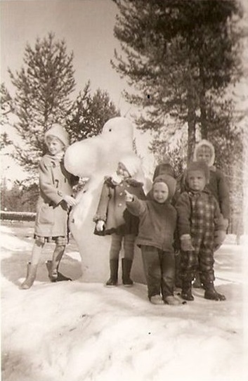 Muumilumiukko ja pieniä lapsia poseeraamassa sen edessä