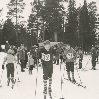 Poikia lähdössä hiihtokilpailuun numerolaput rinnassa 1950-luvun Leppiniemessä